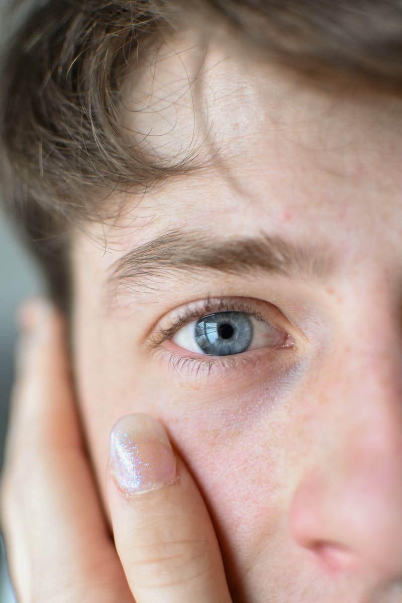 Close-up shot of a young man with blue eyes and hand on face.