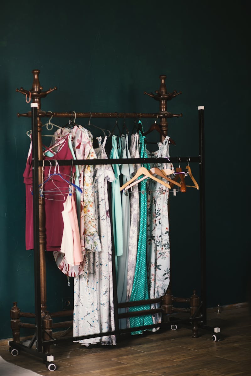 A stylish collection of dresses on a wooden clothes rack against a dark wall, creating a chic aesthetic.