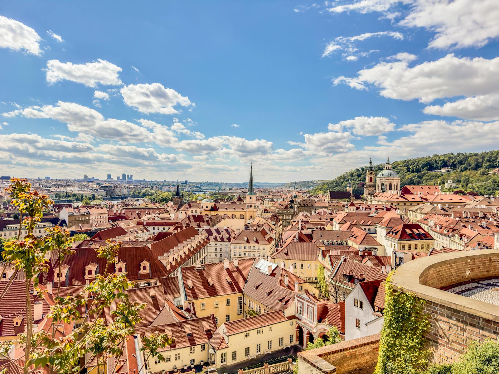 Discover the picturesque rooftops of Prague, featuring iconic architecture and vibrant colors under a clear blue sky.