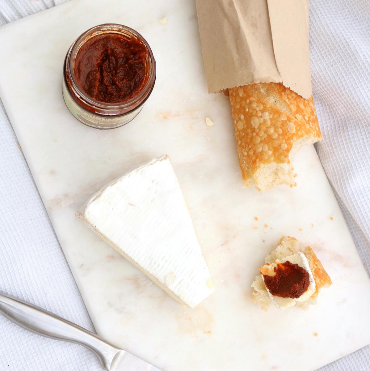 Top view of brie, baguette, and spread on a marble board for breakfast.