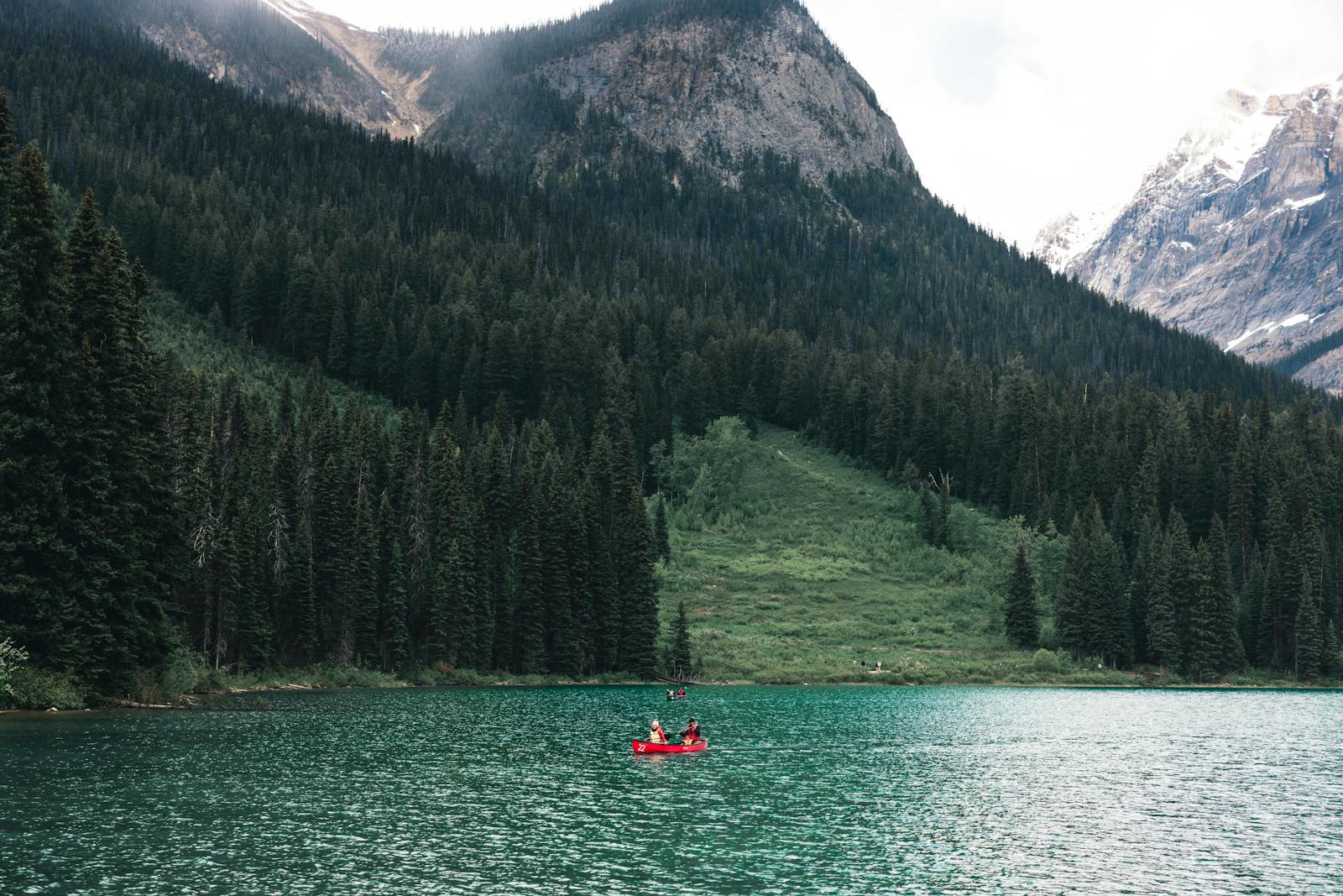 Scenic view of canoeing on a turquoise lake surrounded by mountains and forest in Field, BC, Canada.