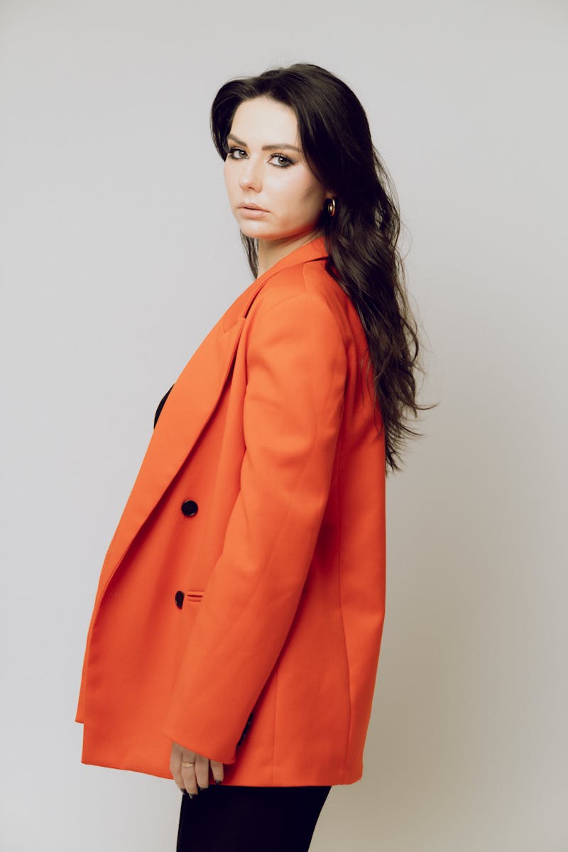 Elegant portrait of a woman wearing a vibrant red jacket, poised against a white background.