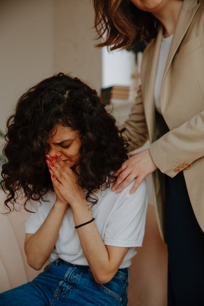 A young woman receives comforting support in a counseling session, highlighting empathy and mental health awareness.