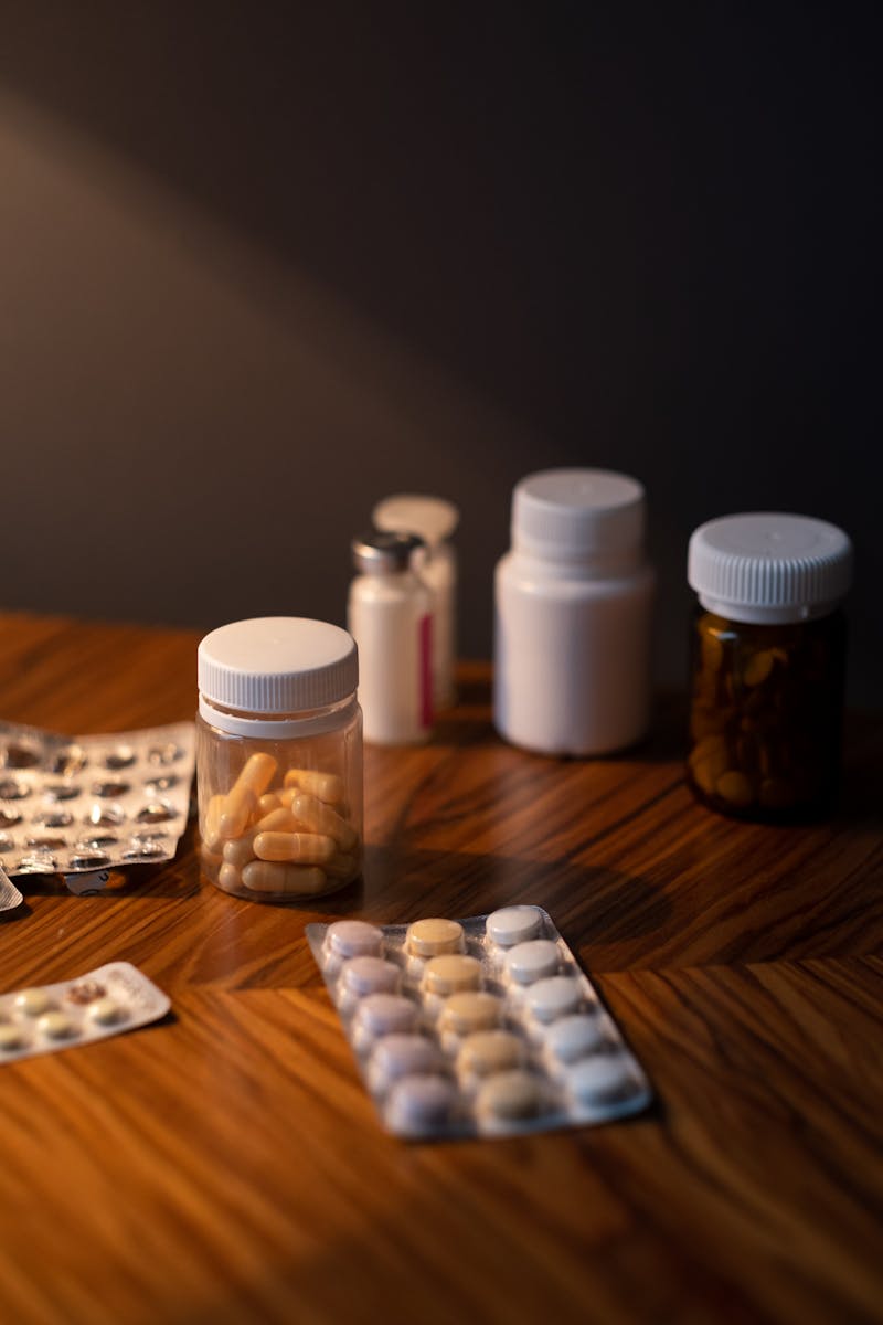 Various pills and medicine bottles on a wooden table, ideal for healthcare themes.