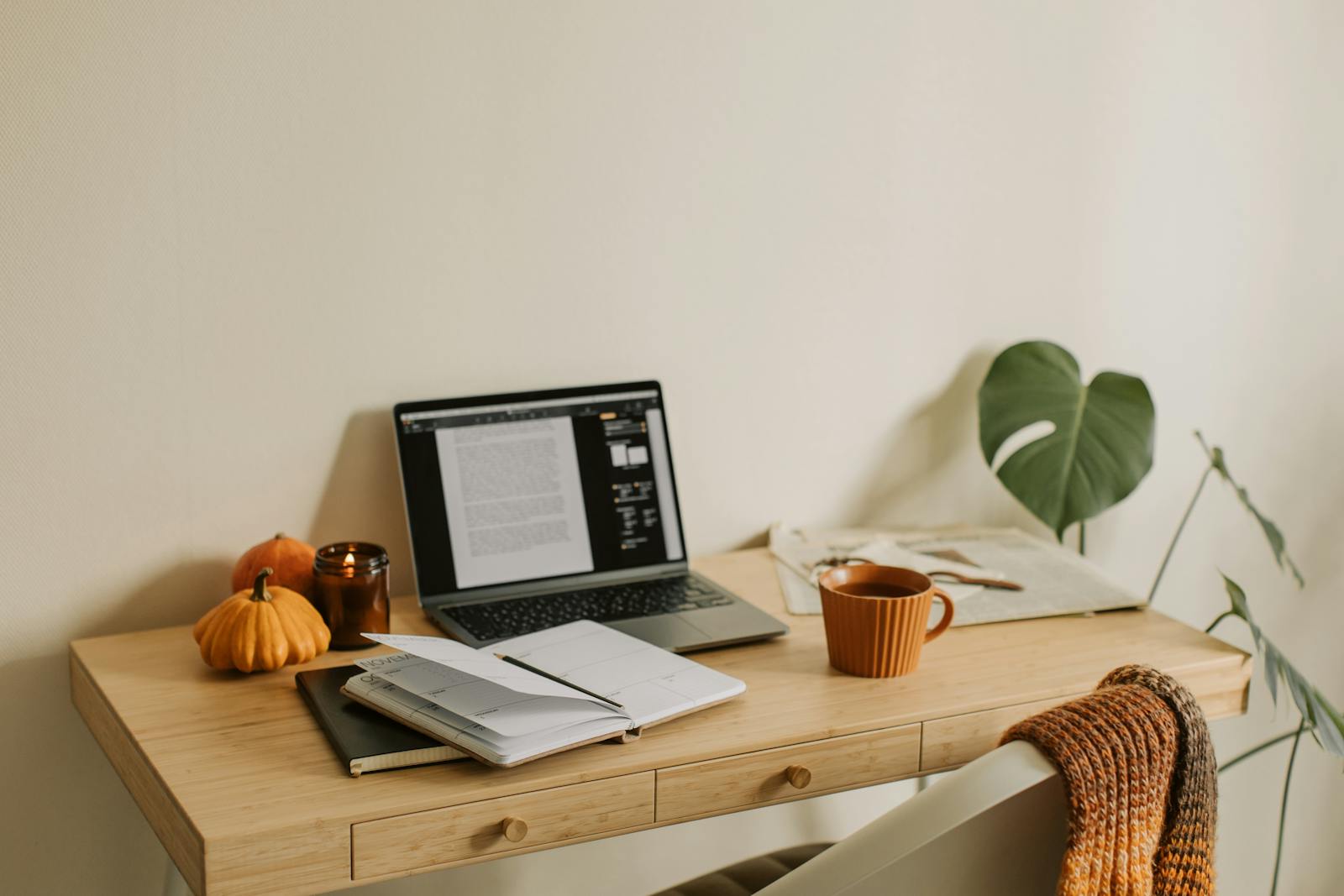 Warm and inviting home office with autumn decor, laptop, and mug.